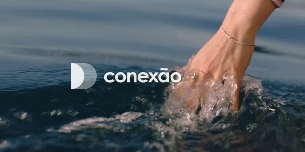Pessoa passando a mão sobre a água do mar com a logo da Decolar e a palavra "conexão" sobre a imagem
