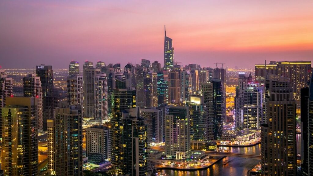 Muitos prédios com luzes em um fim de tarde nos Emirados Árabes