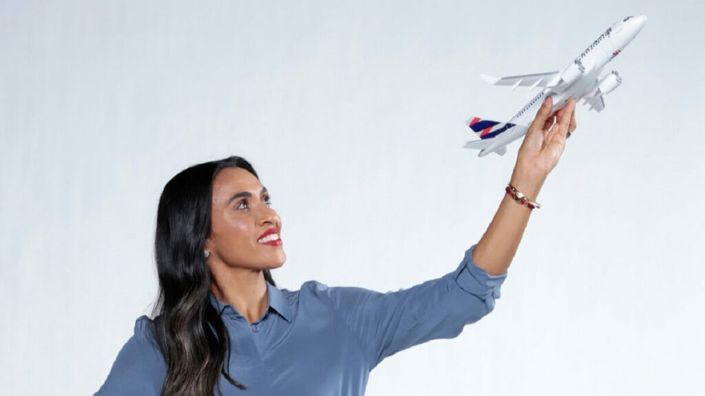 Marta, jogadora da seleção feminina de futebol do Brasil com uma miniatura do avião da Latam em um fundo branco